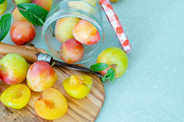 Plums cut on kitchen table and blue background with wooden basket.