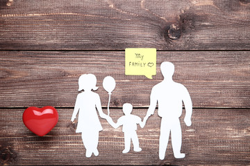 Family figures with red heart and speech bubble on wooden table