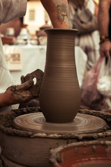 Hands of a potter shaping a clay pot on a potter wheel