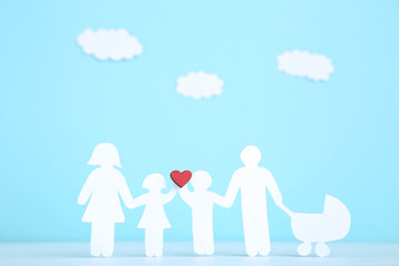Paper family figures with red heart and clouds on blue background