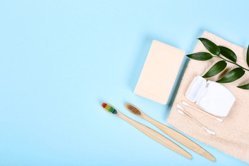 Bamboo toothbrushes with soap, cotton sticks and dental floss on blue background