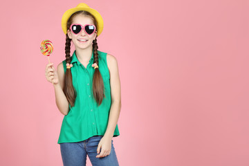 Beautiful young girl with sweet lollipop on pink background