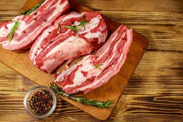 Raw pork ribs with spices and rosemary on wooden table. Top view