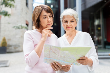 tourism, travel and friendship concept - happy senior women with city map on street in tallinn