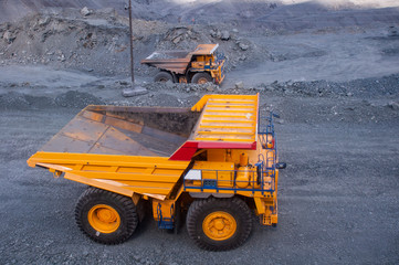 mining machinery works in a quarry. Trucks are transporting ore. excavators load ore into dump trucks.