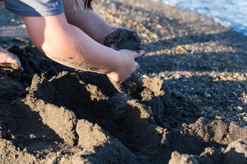 Childs hands playing on beach building sand structures