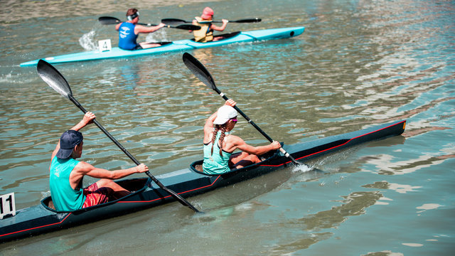 Young man and woman athlete on rowing kayak on lake, competition