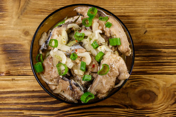 Marinated carp in glass bowl on wooden table. Top view