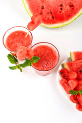 Watermelon smoothie fresh juice with mint, pieces of watermelon in the shape of hearts and slices of watermelon. Healthy drinks in glasses on a white background.