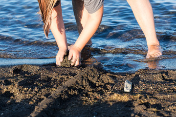 Child building troughs and trenches around their sand castle