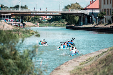 Team of a young men on rowing kayak on lake, competition
