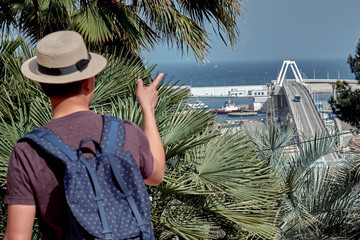 Young tourist in a hat with a backpack pointing to the bridge to Port of Barcelona - 287442342