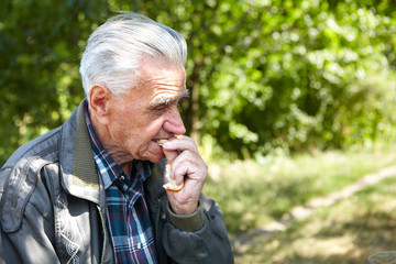 Elderly poor man eating bread