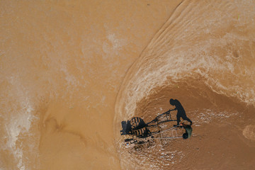 Asian man working on the rice fields with the tractor. Image taken from above with a drone. 
