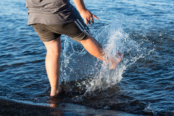 Child kicks the water splashing the lake
