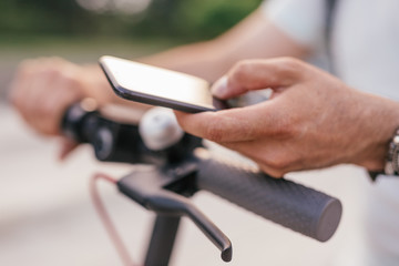 Crop man with electric scooter using smartphone
