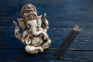 Fototapeta na wymiar Hindu god Ganesh on black background. Statue on wooden table