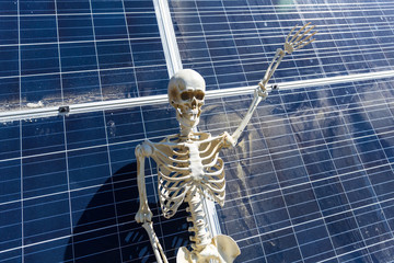 Skeleton leaning on solar panels in the desert
