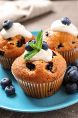 Plate of tasty muffins and blueberries on table, closeup