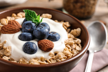 Bowl of tasty oatmeal with blueberries and yogurt on table, closeup