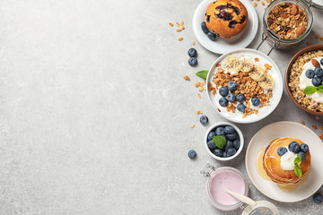 Different tasty dishes with blueberries on grey table, flat lay. Space for text