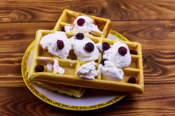 Belgian waffles with ice cream and blackberries on wooden table