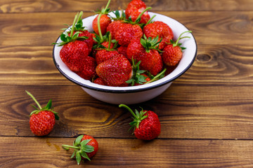 Fresh ripe strawberry in white bowl on a wooden table