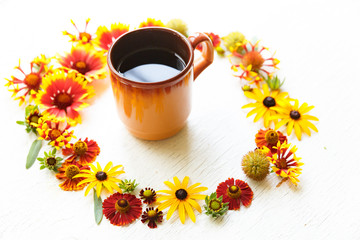 Cup of tea in middle of circle flower composition on a wooden white background