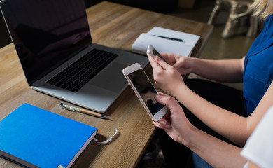 Close up women chatting on cell telephone in internet during work on laptop computer. Businesswomen using mobile phones during webinar on net-book. Managers using cellphones and notebook. Blank screen