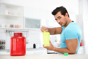 Young athletic man preparing protein shake in kitchen
