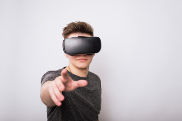 A teenager in a viar glasses pulls his hand to the screen. The virtual reality