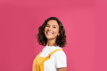 Happy young woman in casual outfit on pink background