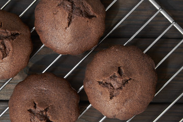 Homemade chocolate muffins on metal oven grill. Dark wooden background, closeup, selective focus, top view