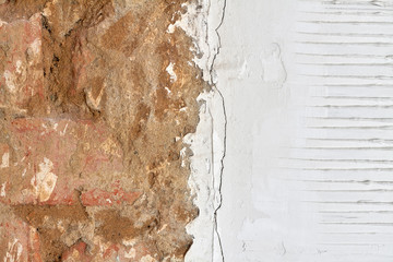 White grooved stucco on wall with a part red brick wall. Old plaster texture or background. Closeup