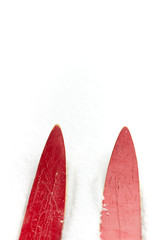 Red ski isolated on the white surface of snow , vertical, closeup, winter holidays festive concept
