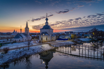Russian town Suzdal at sunset. Church of the Epiphany and the bridge over the Kamenka river – the beauty of the Russian province. 
