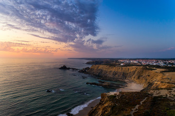 Aerial view of the Zambujeira do Mar village and beach at sunset, in Alentejo, Portugal;