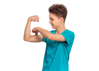 Portrait of funny teen boy raised his hands and shows biceps, isolated on white background. Handsome teenage young boy shows biceps. Happy strong child flexing biceps.