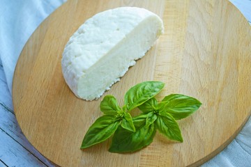 Home-made sliced Adyghe cheese lying on wooden board.