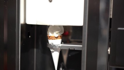 Human hand holding cone with twisted ice cream from machine 