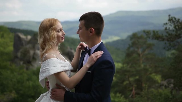 The bride and groom are hugging while standing on top of the mountain. Wedding walk in the forest. Video shot in the Carpathians in the warm summer.
