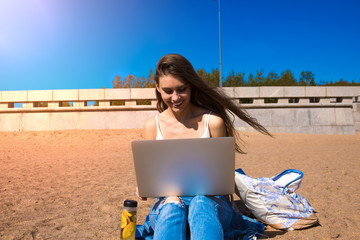 Happy smiling woman freelance copywriter typing text on laptop computer while relaxing outdoors on...