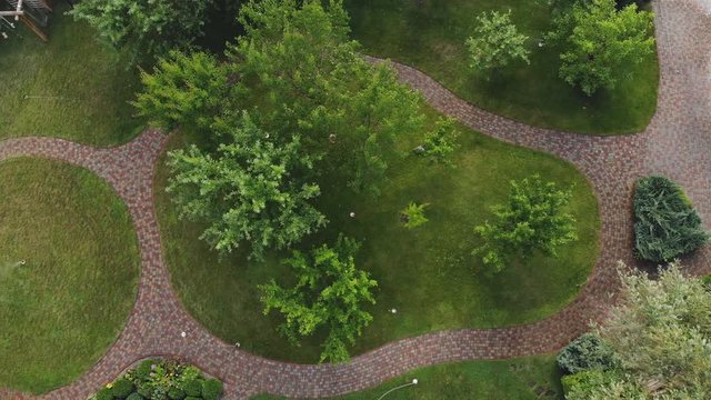 Aerial drone view of landscape automatic garden watering system with different sprinklers installed under turf. Landscape design with lawn hills and fruit garden irrigated with smart sprayers 