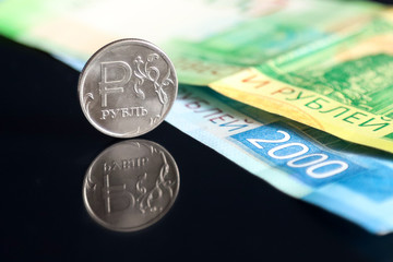 Russian ruble coin and Russian banknotes on a black mirroring surface