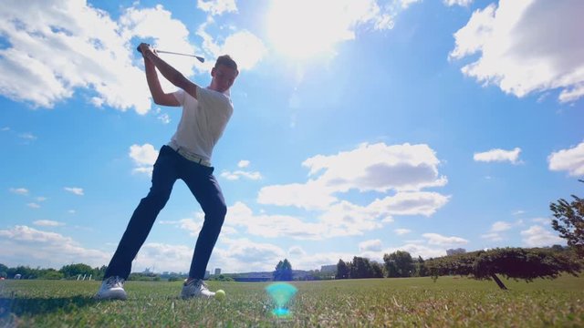 Male golfer hits a ball on a course while training.