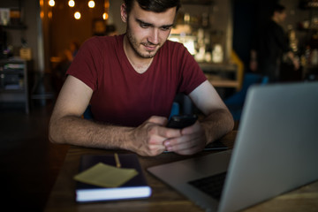 Man owner online business in internet reading notification on mobile phone while sitting with...