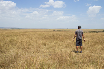 Naklejka na ściany i meble A young man looking for animals in the Masai Mara. Kenya