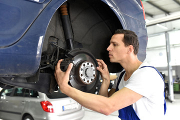 car mechanic repairs brakes of a vehicle on the lifting platform in a workshop