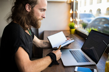 Fashionable college student having webinar via laptop computer using textbook for notary, sitting...