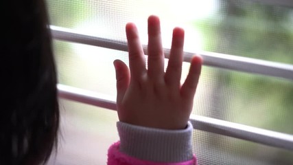 Sad asian little girl looking outside through the window 